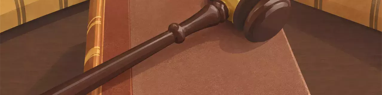 Martillo de madera apoyado sobre un libro de leyes abierto