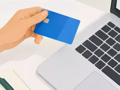Sosteniendo la tarjeta bancaria azul junto al portátil