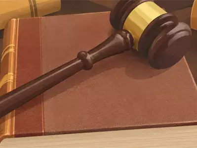 Martillo de madera apoyado sobre un libro de leyes abierto